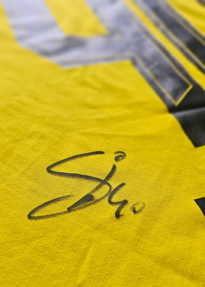 Close-up of signature on yellow Borussia Dortmund football shirt.