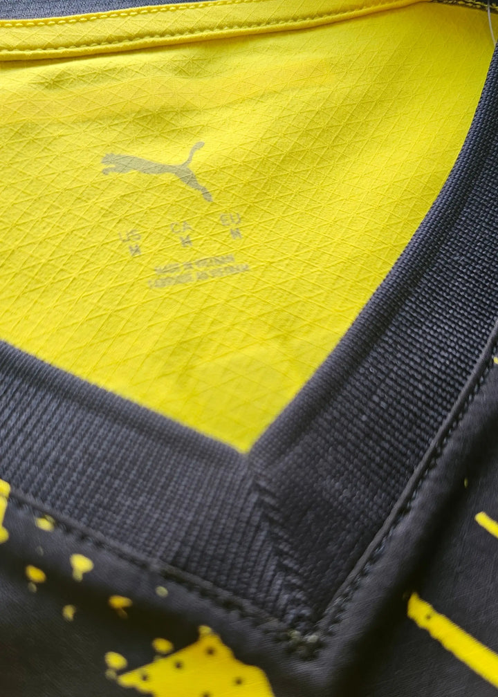 Close-up of the collar area displaying a Puma logo and yellow textile pattern.