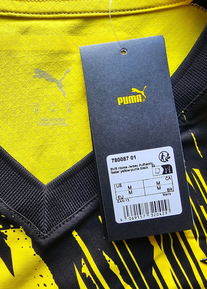 Detail view showing the Puma tag and care instructions on a yellow and black football shirt.