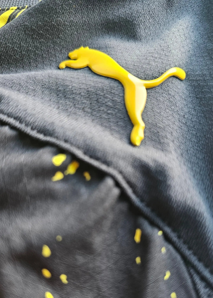 Close-up view of the Puma logo in yellow on a black fabric background.