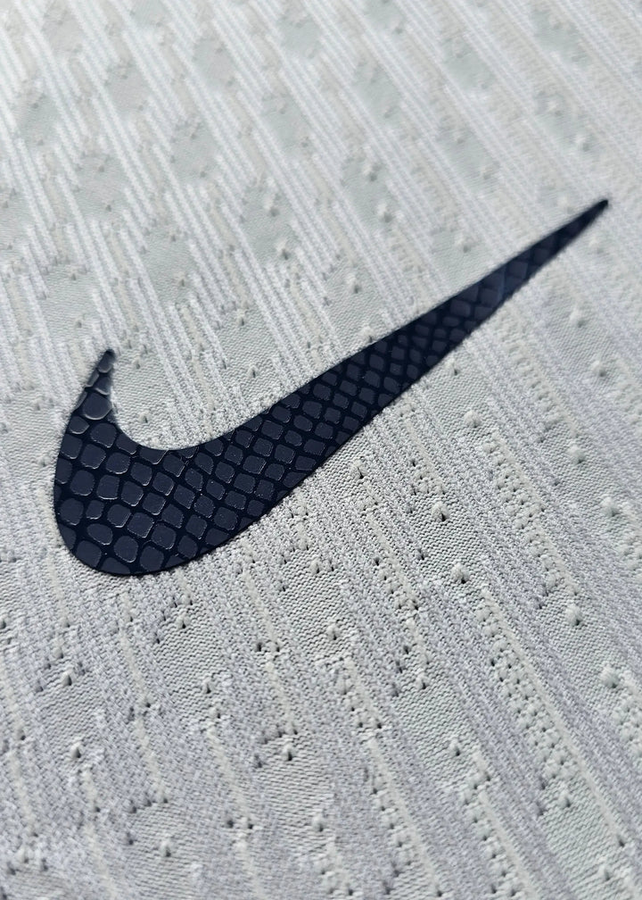 Close-up of the Nike logo on the away football shirt in white and navy colors.