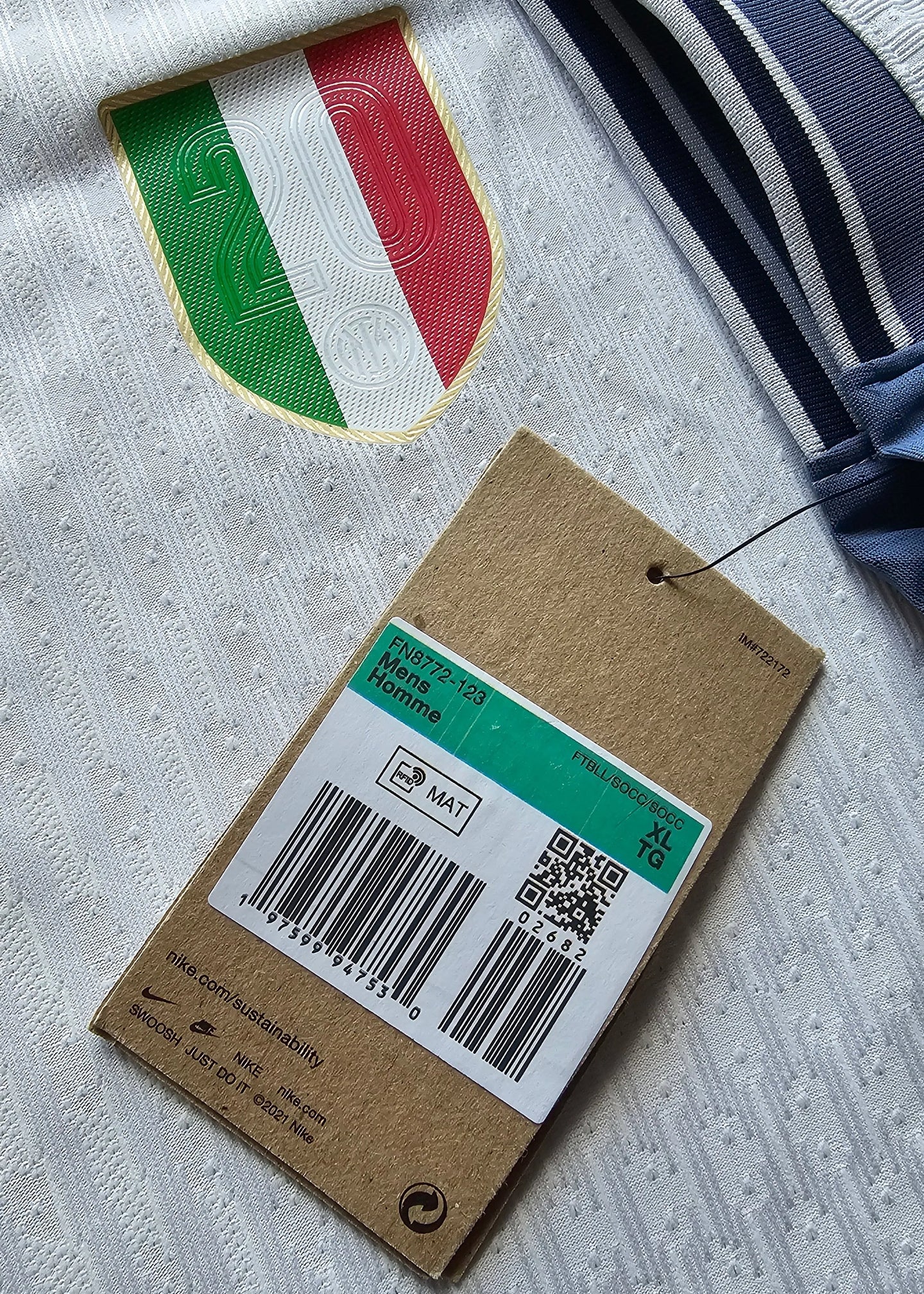Crest detail featuring the Italian flag and number 20 on a white football shirt with a tag below.