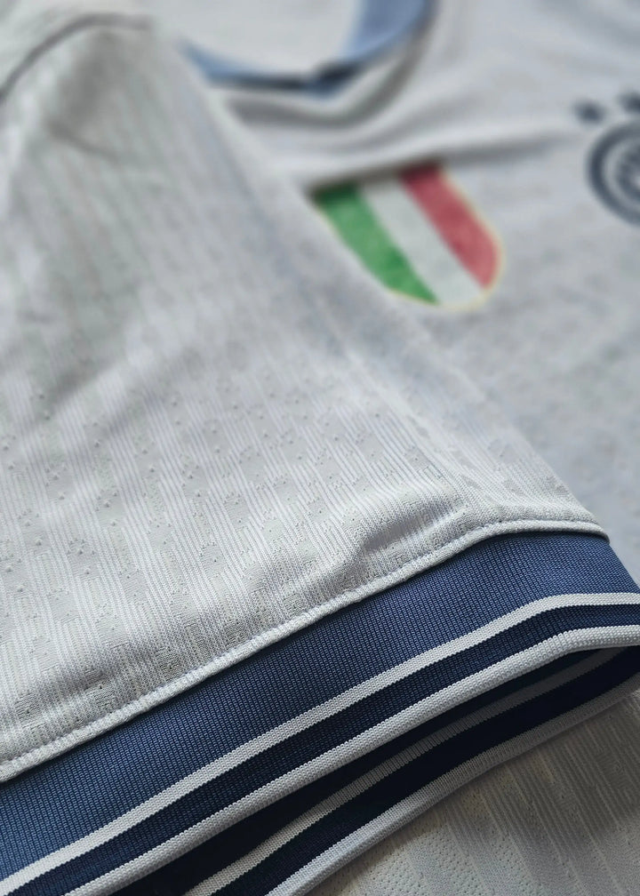 Close-up view of the white shirt with navy trim and Inter Milan crest featuring the Italian flag.