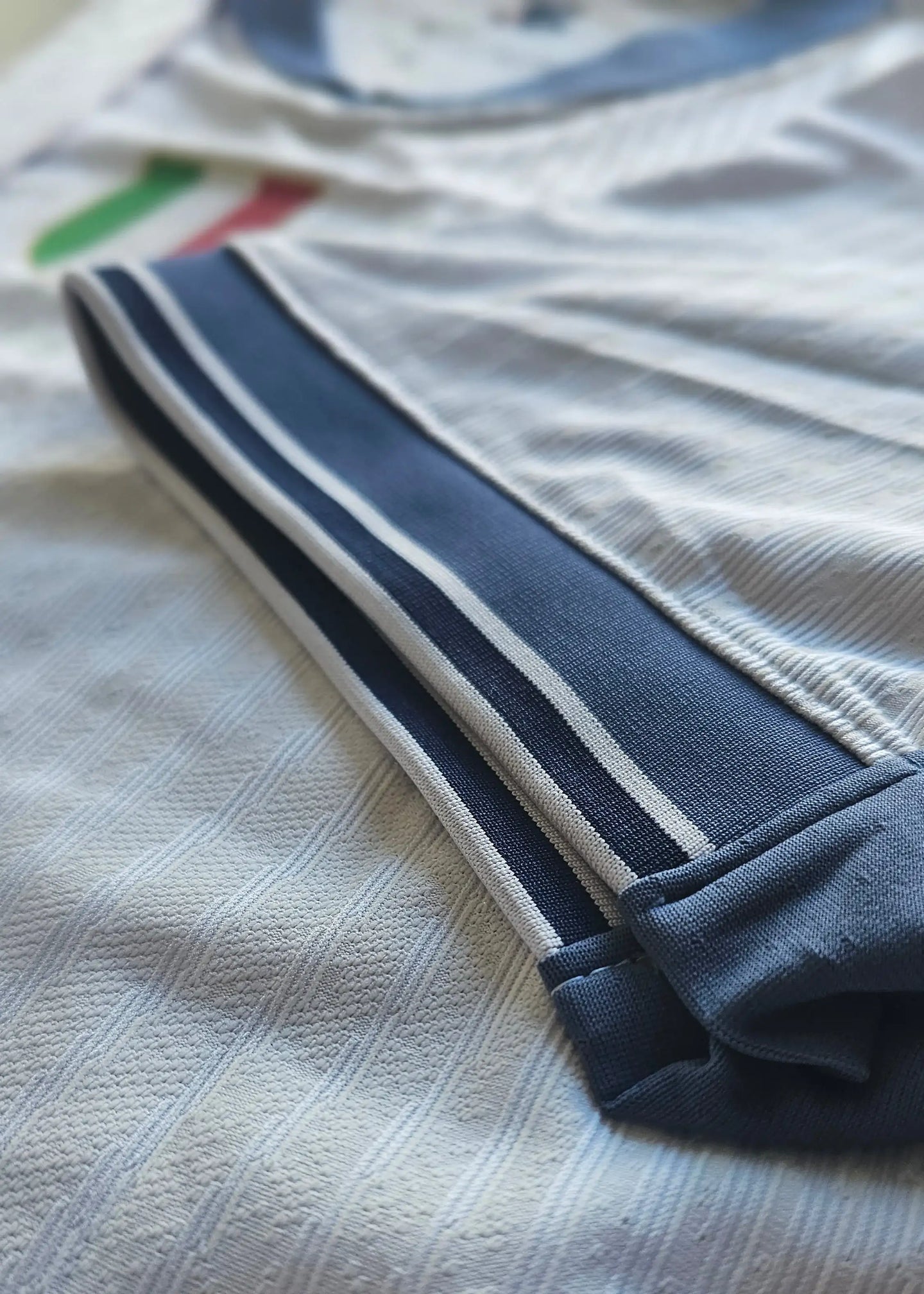 Detail view showing the navy and white sleeve design with stripes on the signed football shirt.