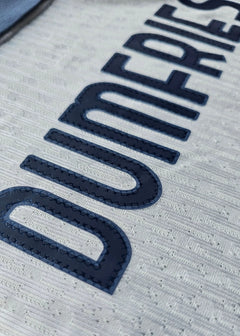 Close-up of the name 'DUMFRIES' in navy on a white background, showcasing texture and detailing.