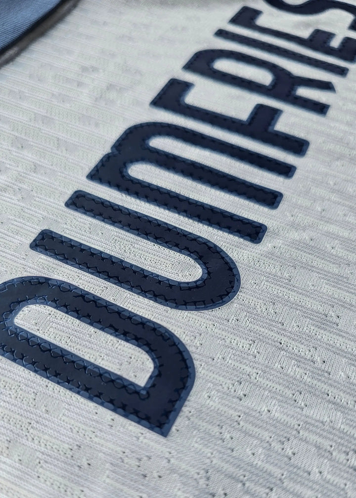 Close-up of the name 'DUMFRIES' in navy on a white background, showcasing texture and detailing.