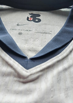 Close-up of collar featuring Nike logo and size label with white and navy colors.
