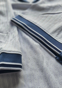 Detail view showing white fabric with navy trim and textured design on the Signed Denzel Dumfries shirt.