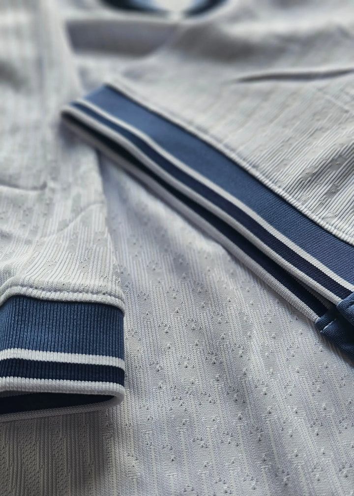 Detail view showing white fabric with navy trim and textured design on the Signed Denzel Dumfries shirt.