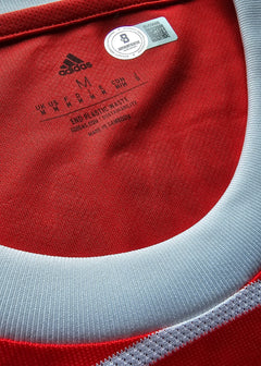 Close-up of a red and white sports jersey with Adidas logo and label.