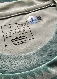 Close-up of Adidas label on a garment with a blue tag.