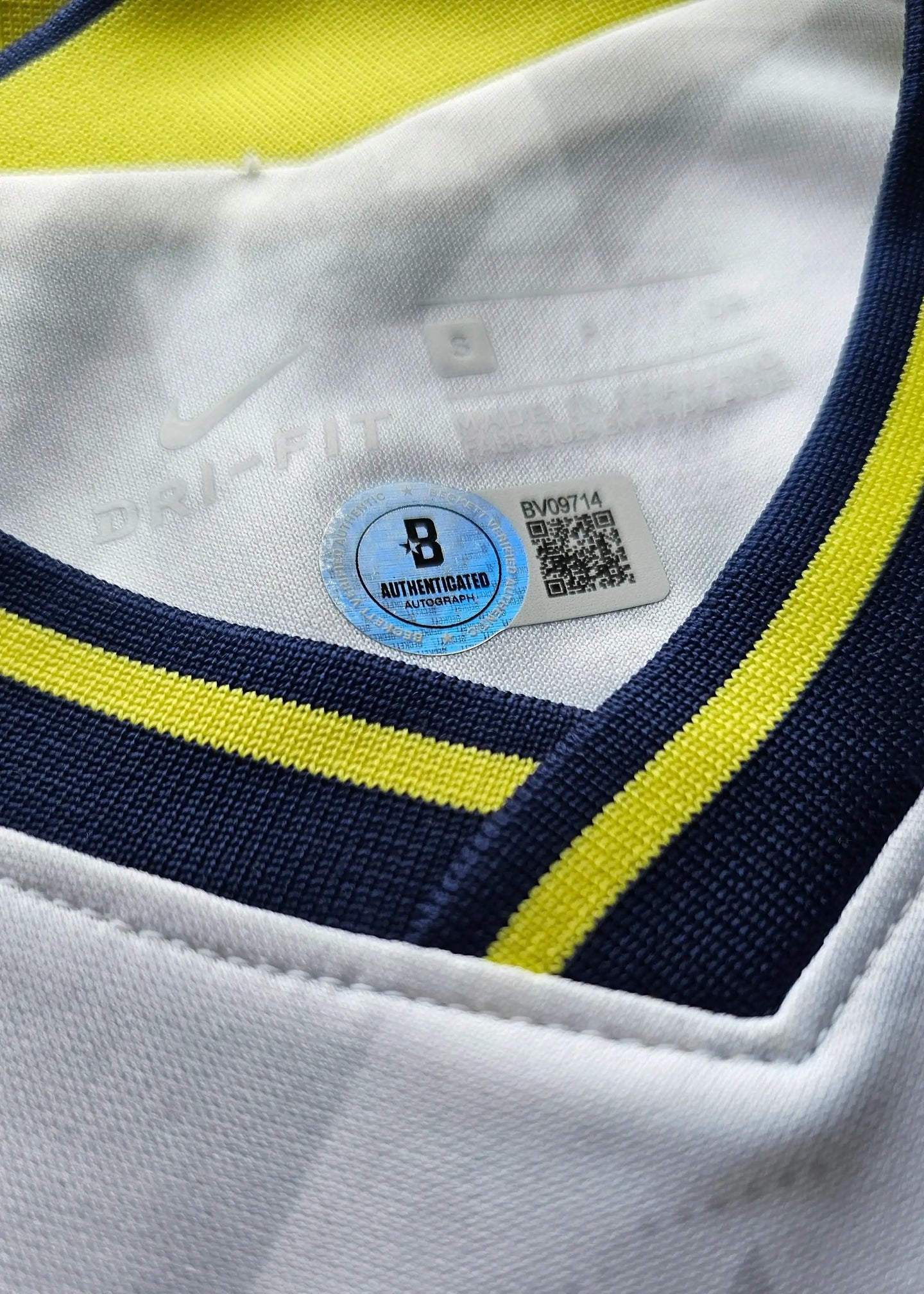 Close-up of a Tottenham jersey with a brand label and QR code on a white background
