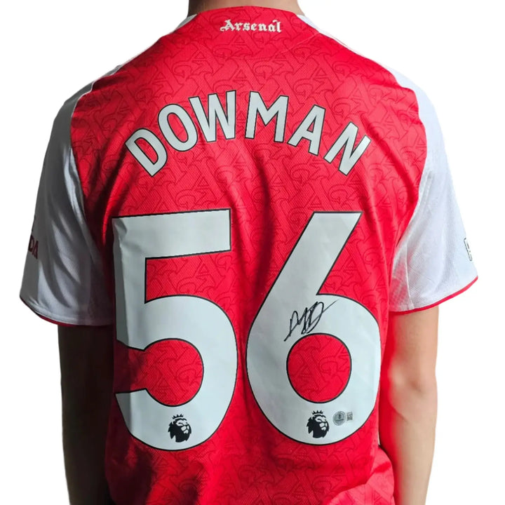 Back view showing Dowman, No. 56, and a visible signature on a red Arsenal football shirt.