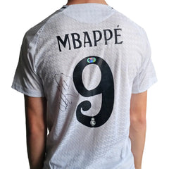 Back view featuring No. 9, name 'MBAPPÉ', and signature on a white football shirt.