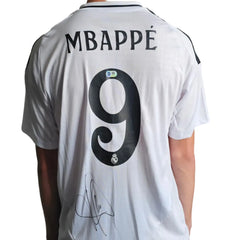 Back view showing Mbappé, No. 9, and a visible signature on a white football shirt.