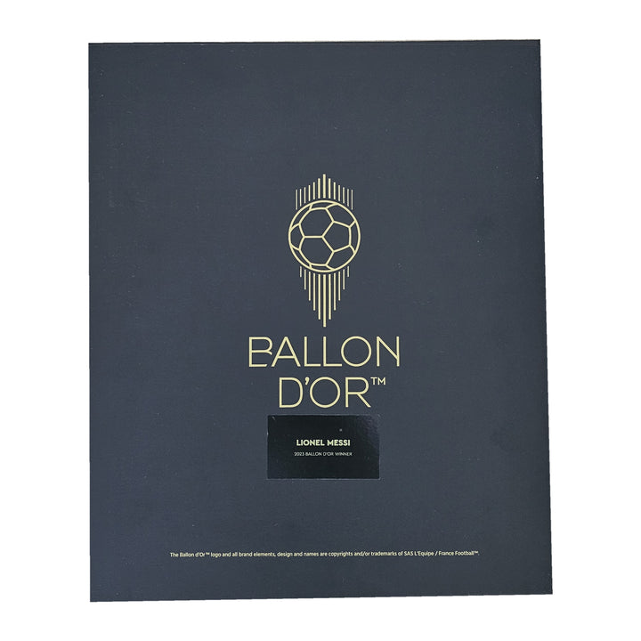 Lid of the Ballon d'Or presentation box, gold ball emblem above the Lionel Messi name plaque, boxed signed Barcelona shirt.