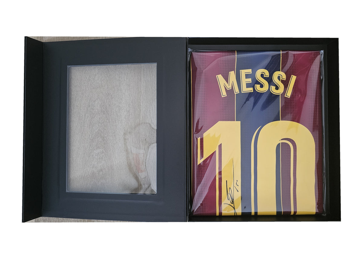 Ballon d'Or box opened to its tray, Messi's signed Barcelona 2020-21 shirt sealed in film beside the empty window panel.
