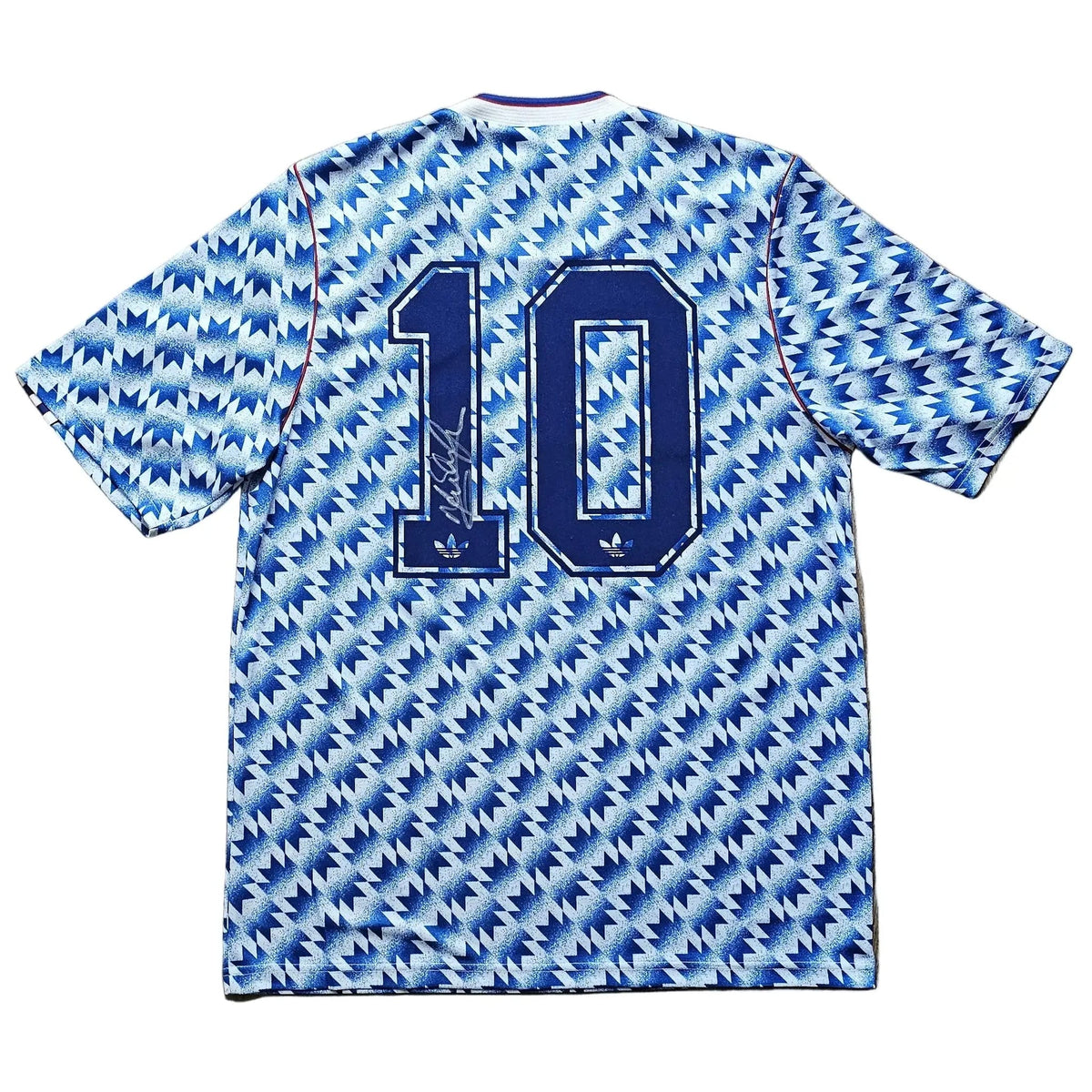 A blue and white patterned short-sleeve soccer jersey with the number 10 printed on the back, laid flat on a light brown wooden floor.