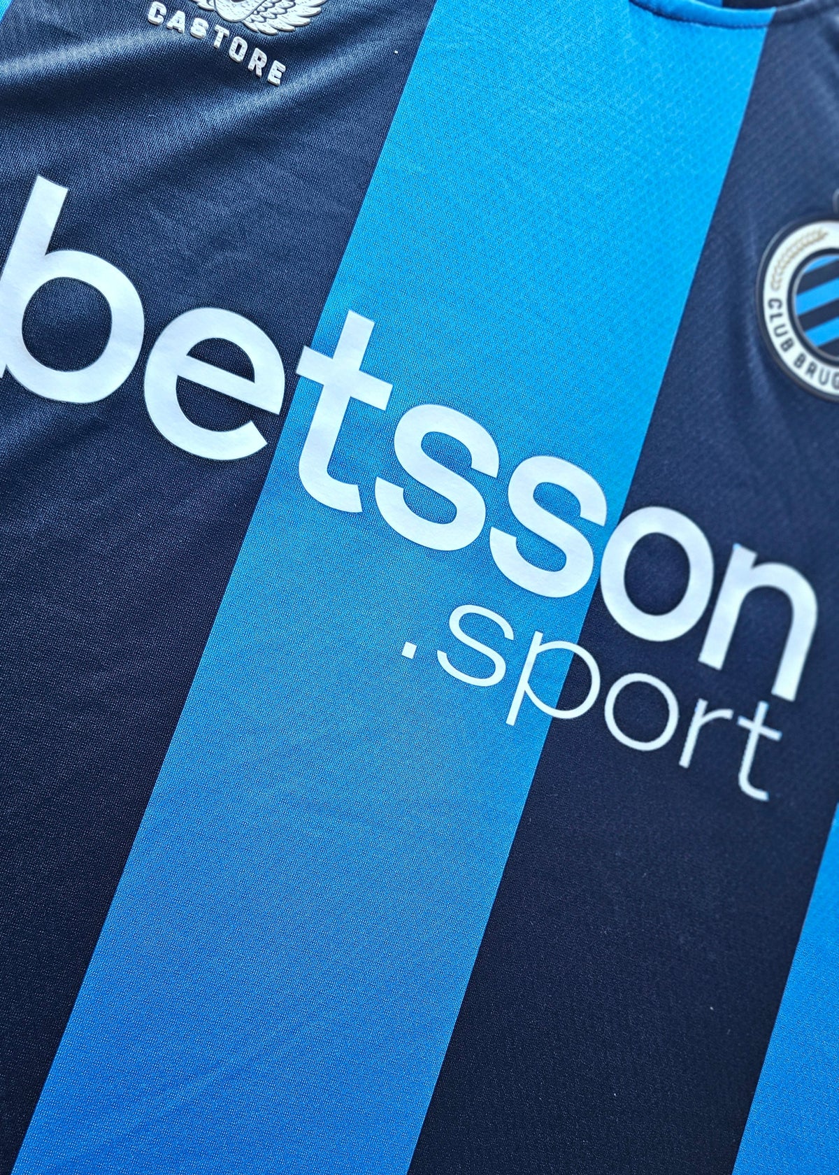 betsson.sport sponsor across the black and blue stripes of the Tian Nai Koren Club Brugge 2026-27 home shirt, Castore logo above