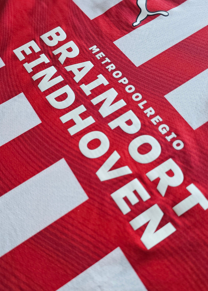 Metropoolregio Brainport Eindhoven sponsor print in white on the red and white PSV 2026-27 home shirt, Bouhamdi 37