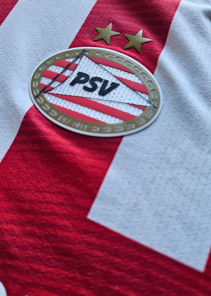 PSV crest with two gold stars on the red and white stripes of the Amir Bouhamdi 2026-27 home shirt, number 37
