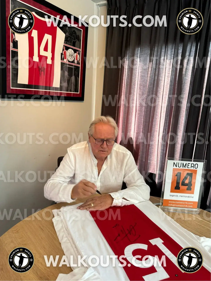 Arie Haan signing a red and white soccer jersey with No. 15, featuring his visible signature.