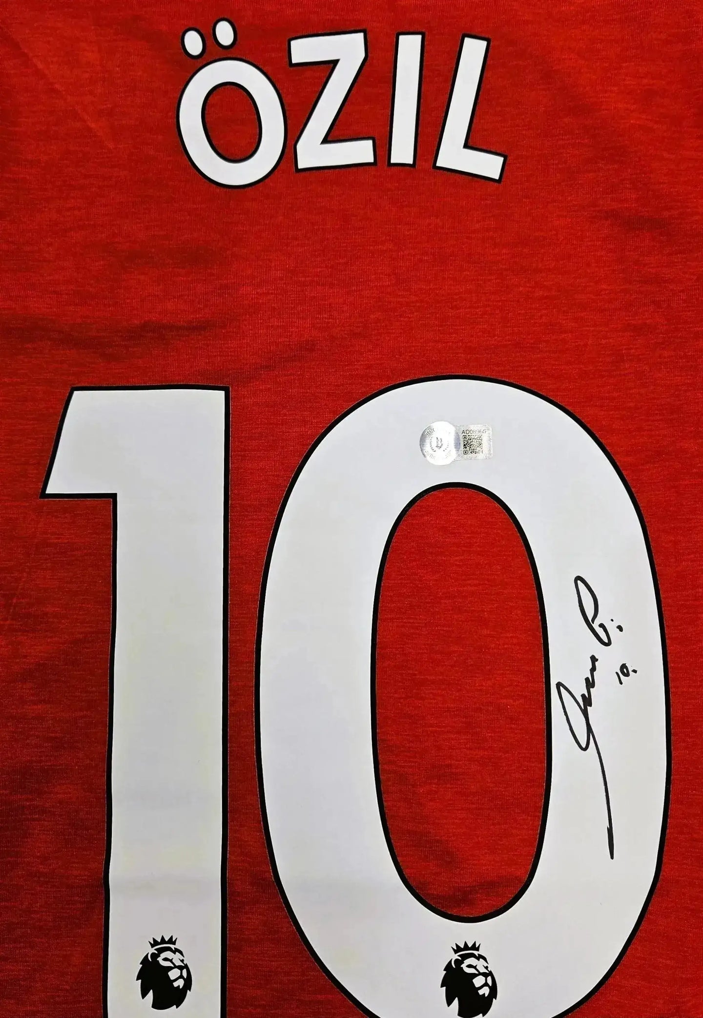 Detail view showcasing No. 10, Özil, and signature on a red Arsenal soccer jersey.