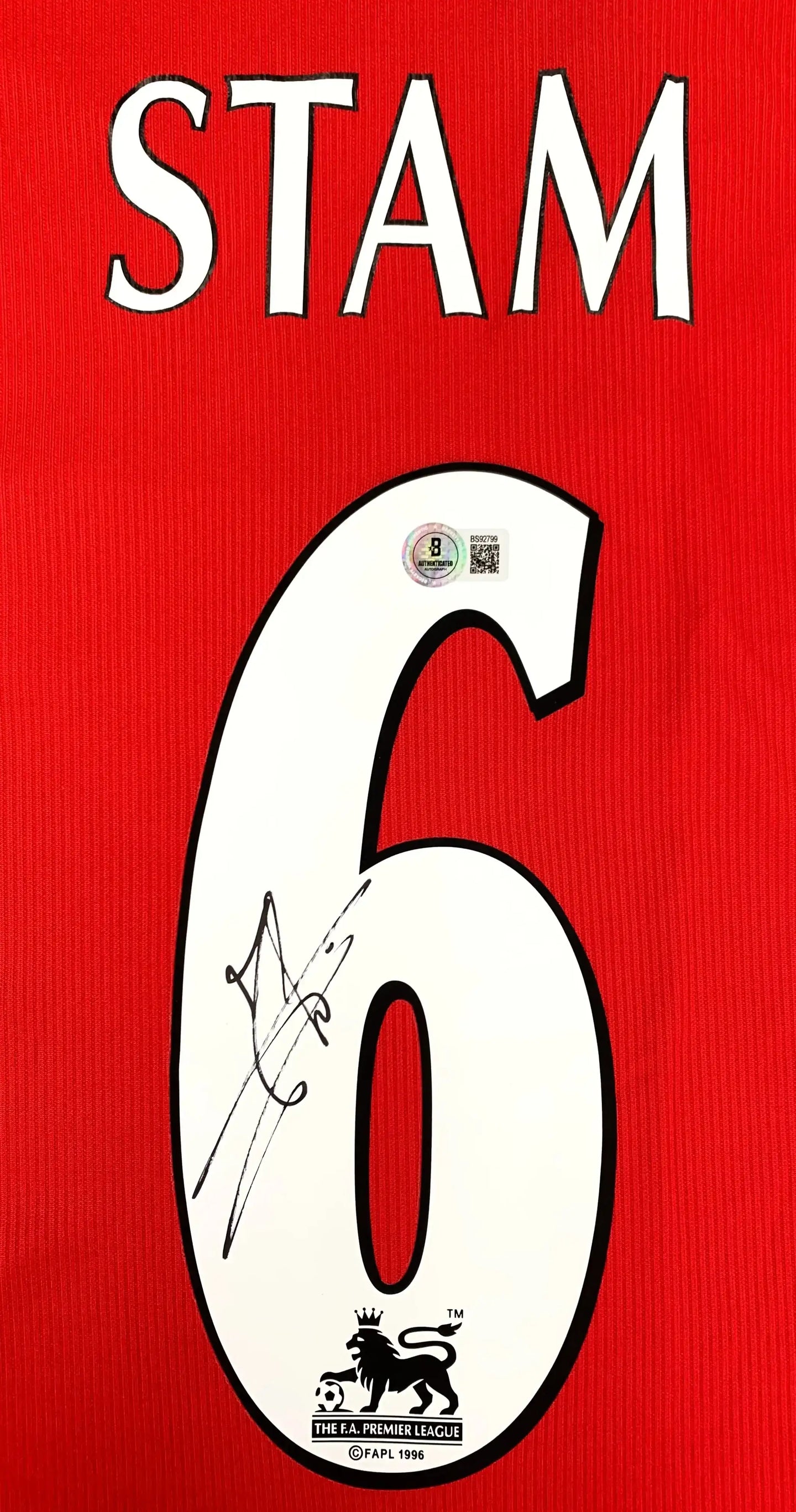 Back view displaying No. 6, Stam, and a visible signature on a red football shirt.