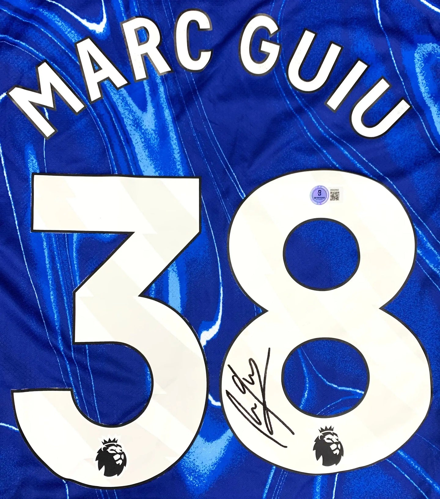 Back view featuring Marc Guiu, No. 38, and a visible signature on a blue football shirt.