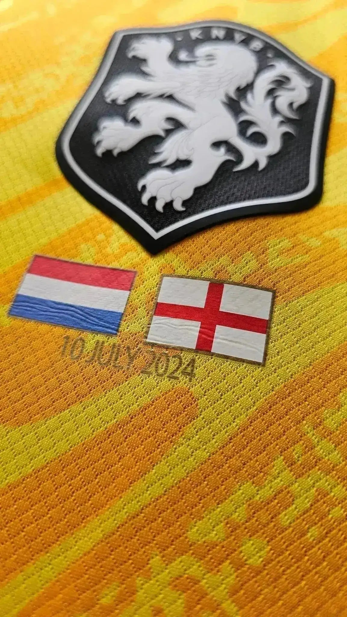 Close-up of the Holland crest and flags with date 10 JULY 2024 on a yellow football shirt.