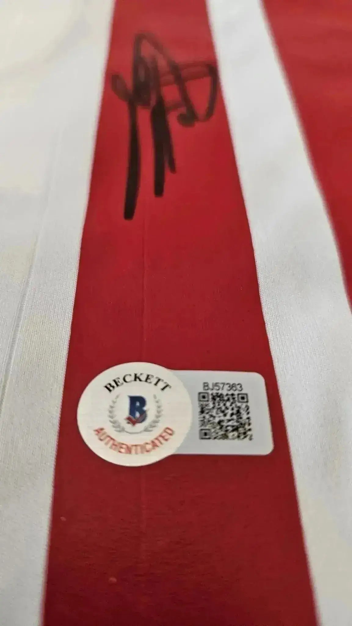 Red fabric with autograph and Beckett authentication sticker visible.