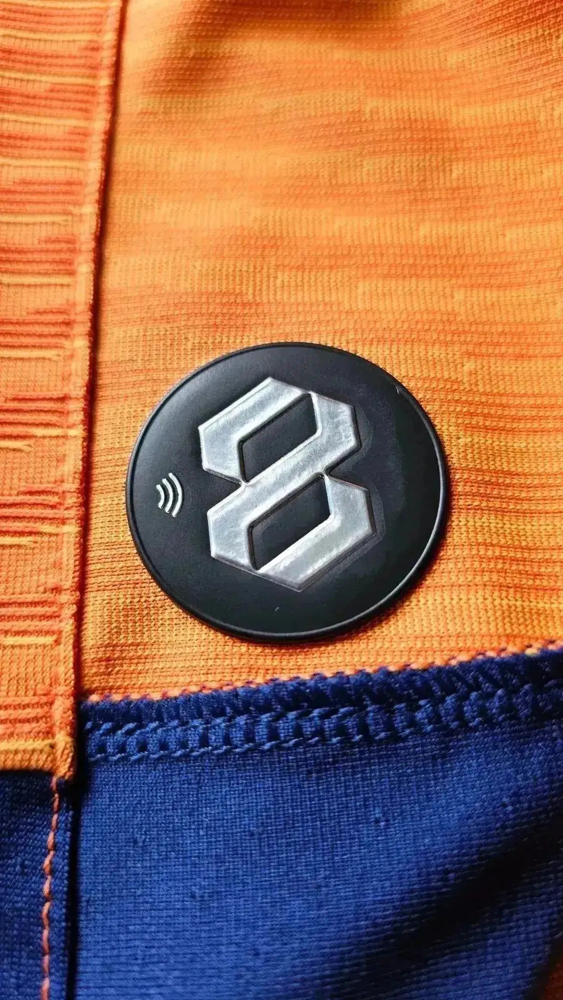 Detail of the black label with the number 8 on the orange and blue football shirt.