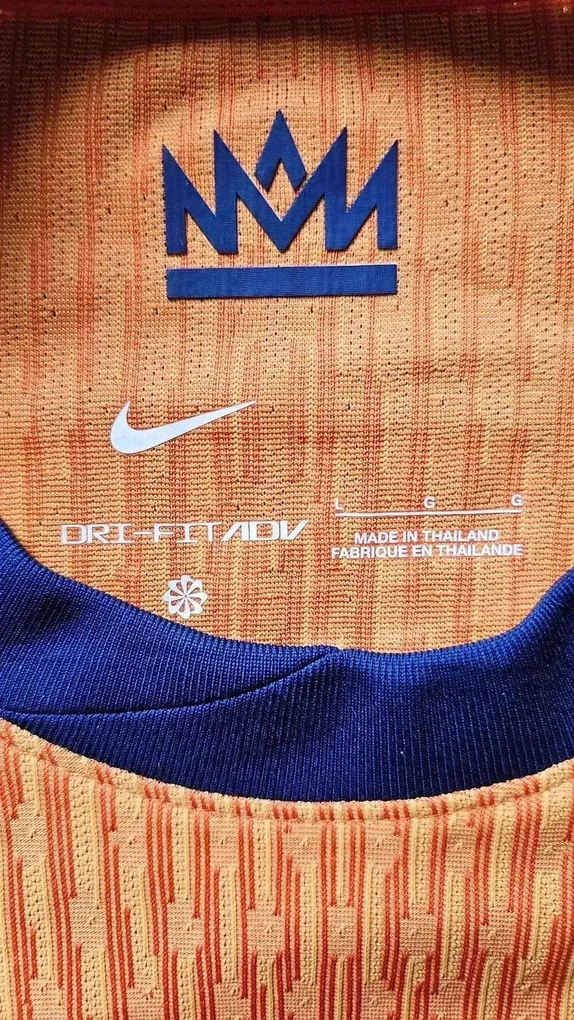 Close-up of orange and blue neck label featuring Nike logo and Dri-Fit ADV text.