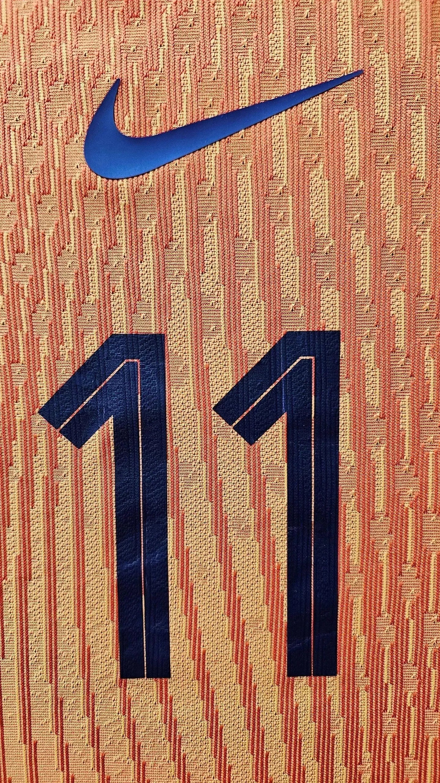 Close-up of the No. 11 in blue on the orange football shirt, featuring Nike logo above.