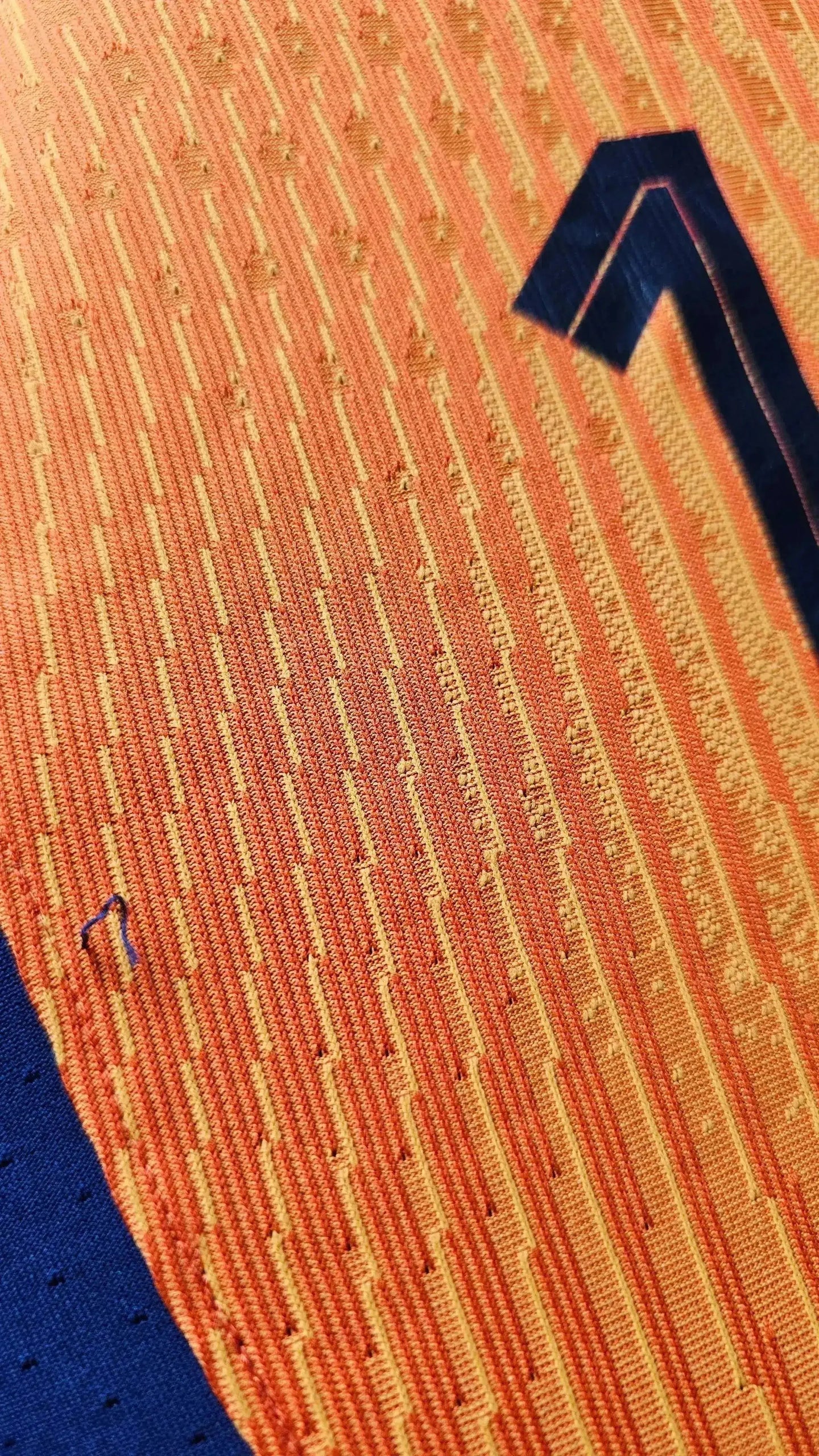 Close-up showing signature detail on orange fabric with blue elements from the Cody Gakpo Holland football shirt.