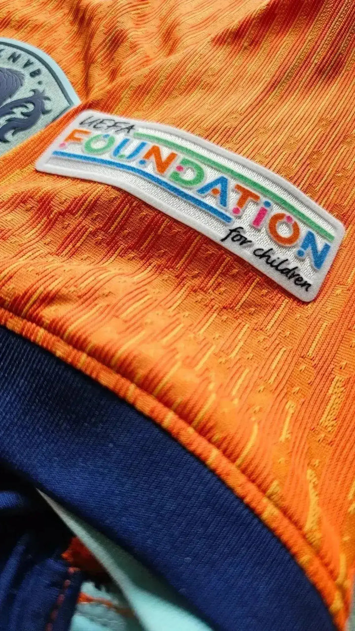 Close-up view showing UEFA FOUNDATION for children patch on orange football shirt.
