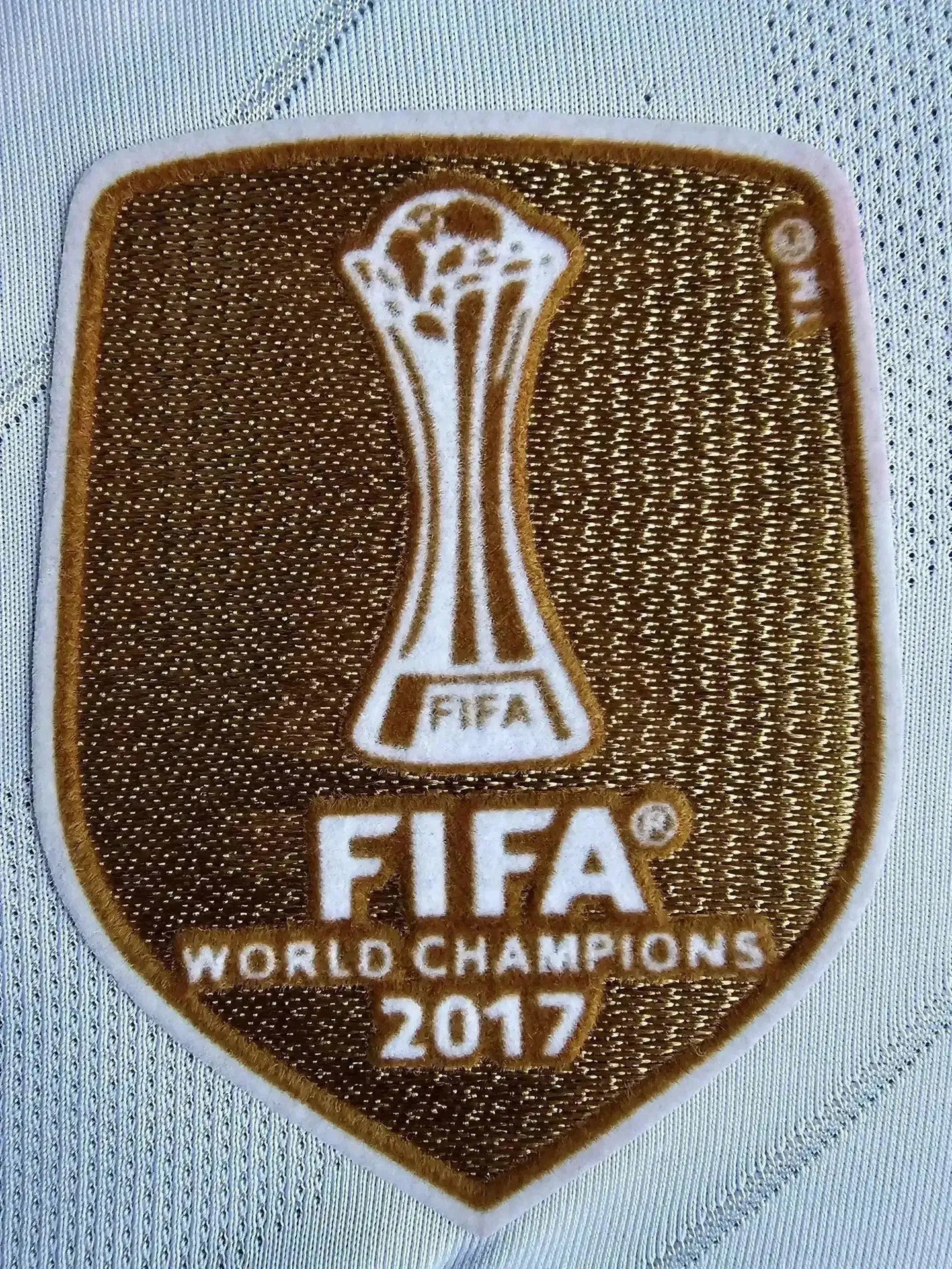 Detail of FIFA World Champions 2017 badge prominently displayed on shirt.