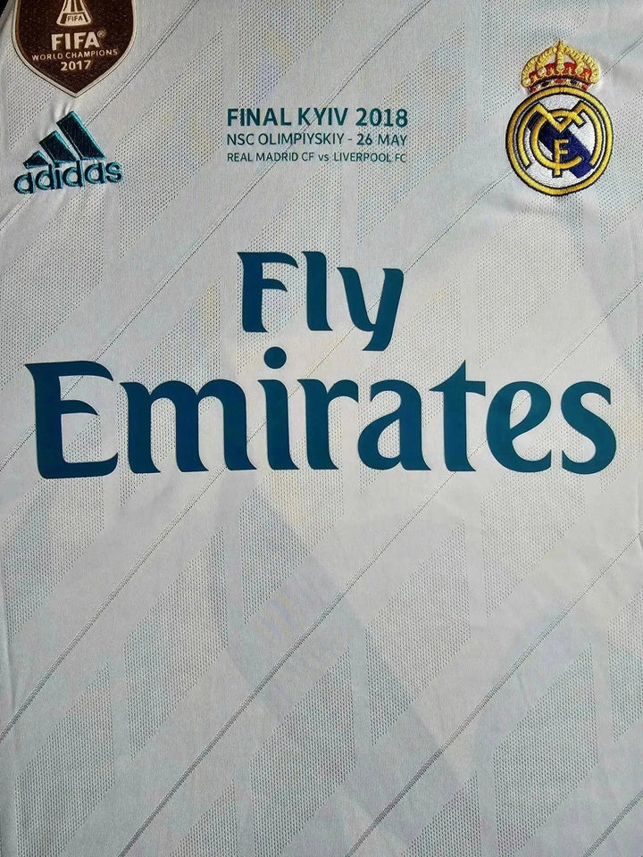 Crest detail featuring Real Madrid CF logo, Fly Emirates sponsor, and FIFA World Champions badge.