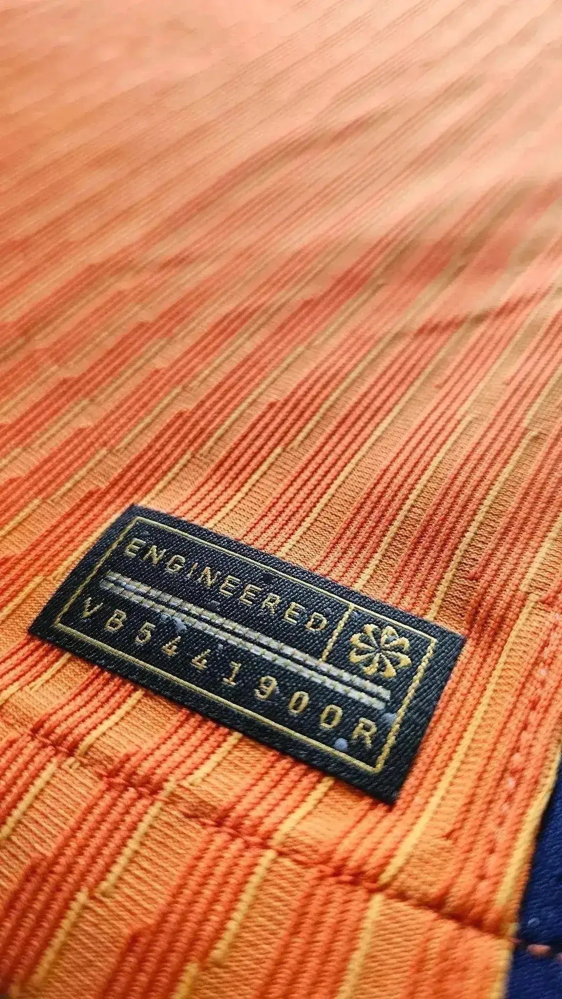Close-up showing the engineered label with text and pattern detail in shades of orange.