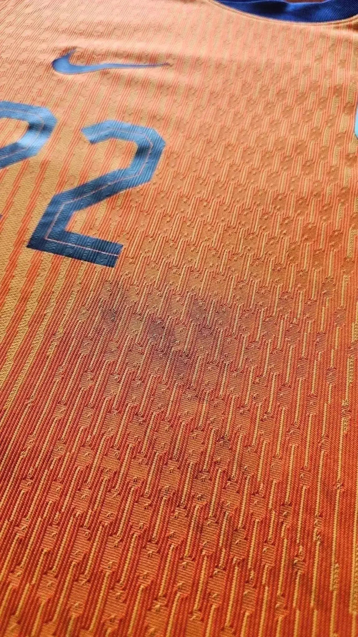 Close-up detail showing the No. 22 on an orange football shirt with game dirt.