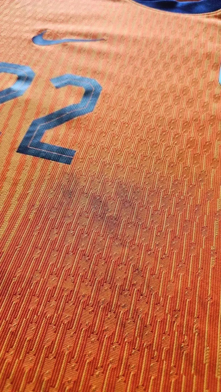 Close-up detail showing the No. 22 on an orange football shirt with game dirt.