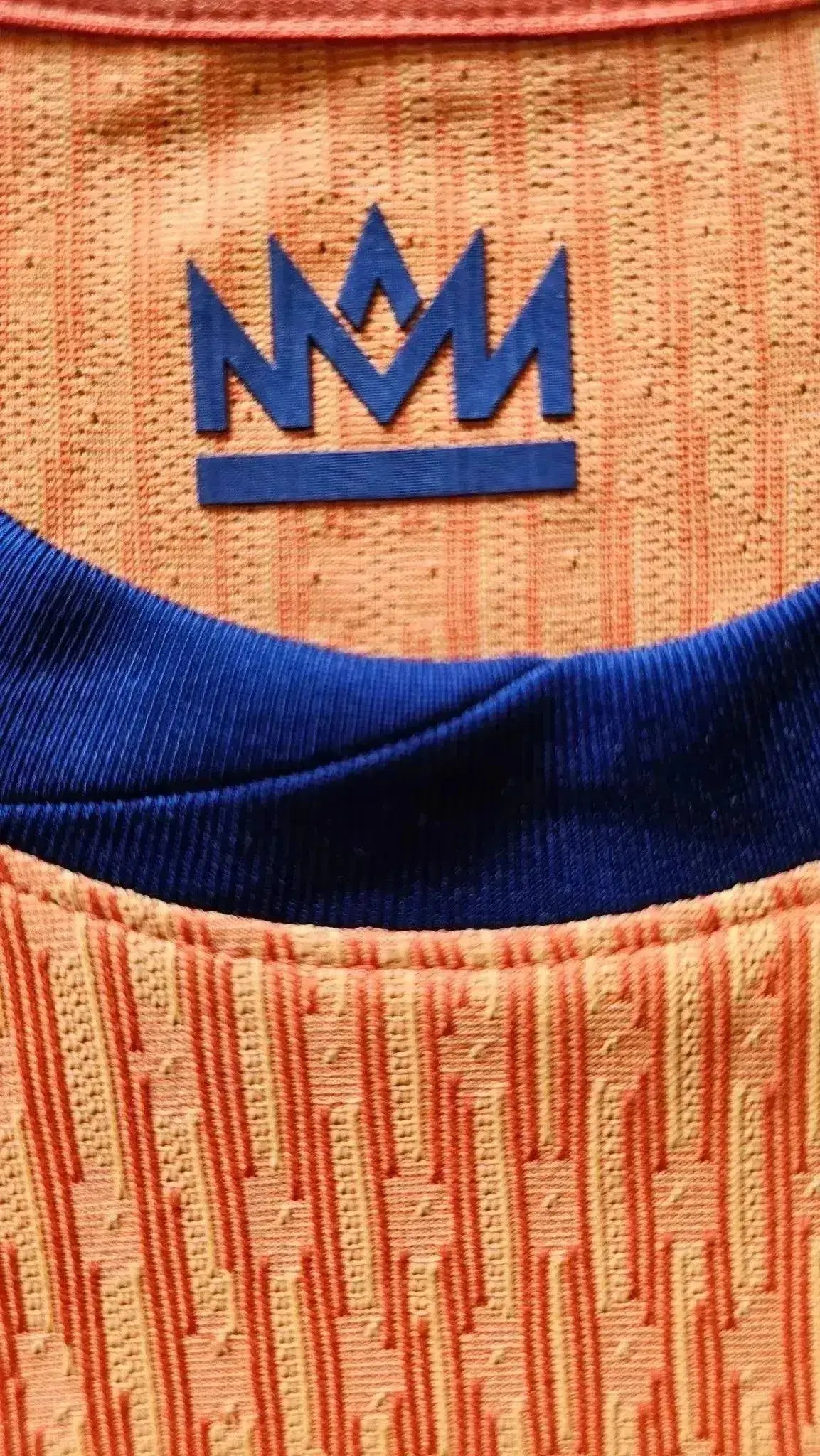 Detail of signature badge in blue on orange fabric with textured patterns.