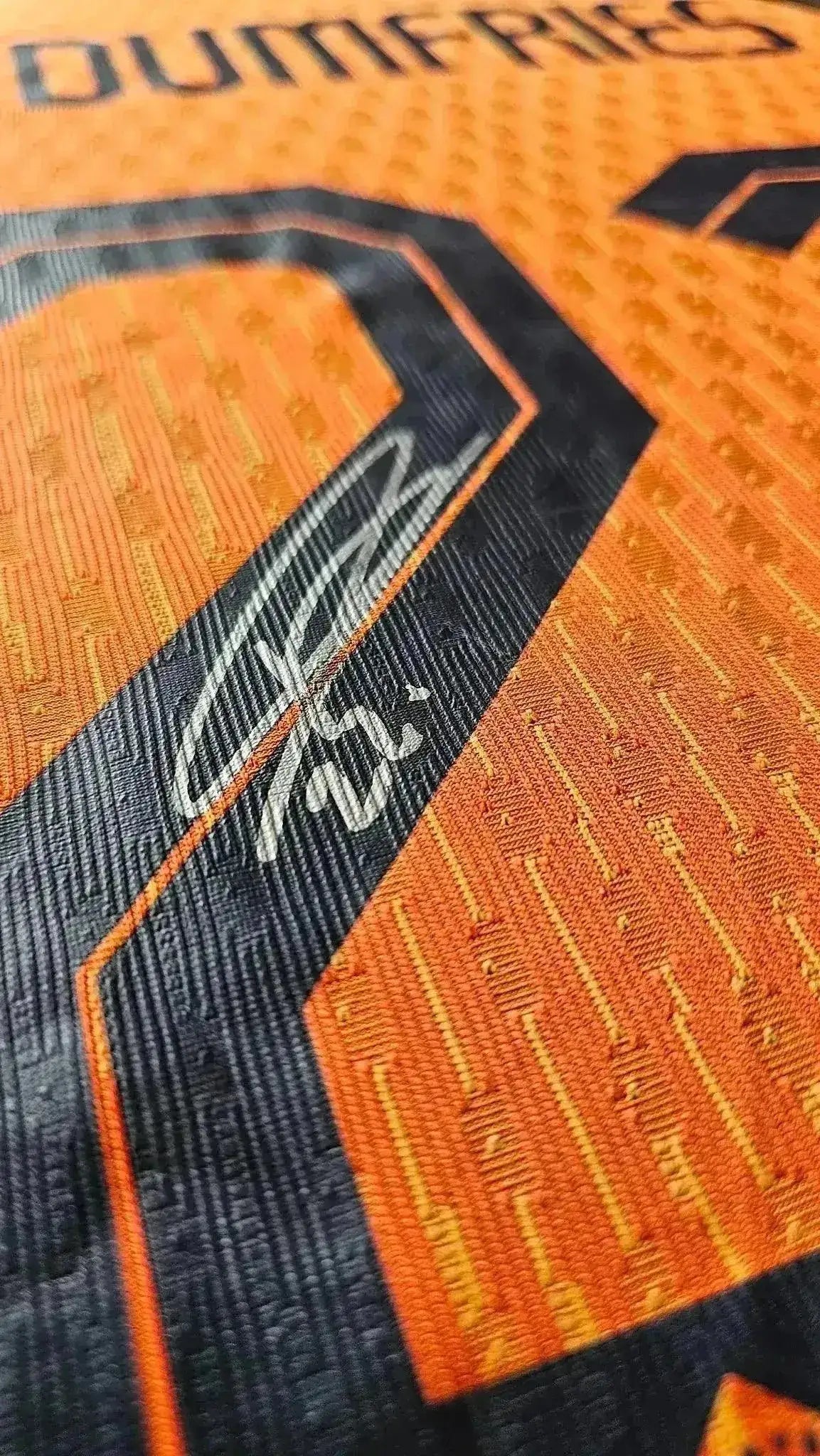 Close-up of Denzel Dumfries signature on orange match-worn Holland football shirt.