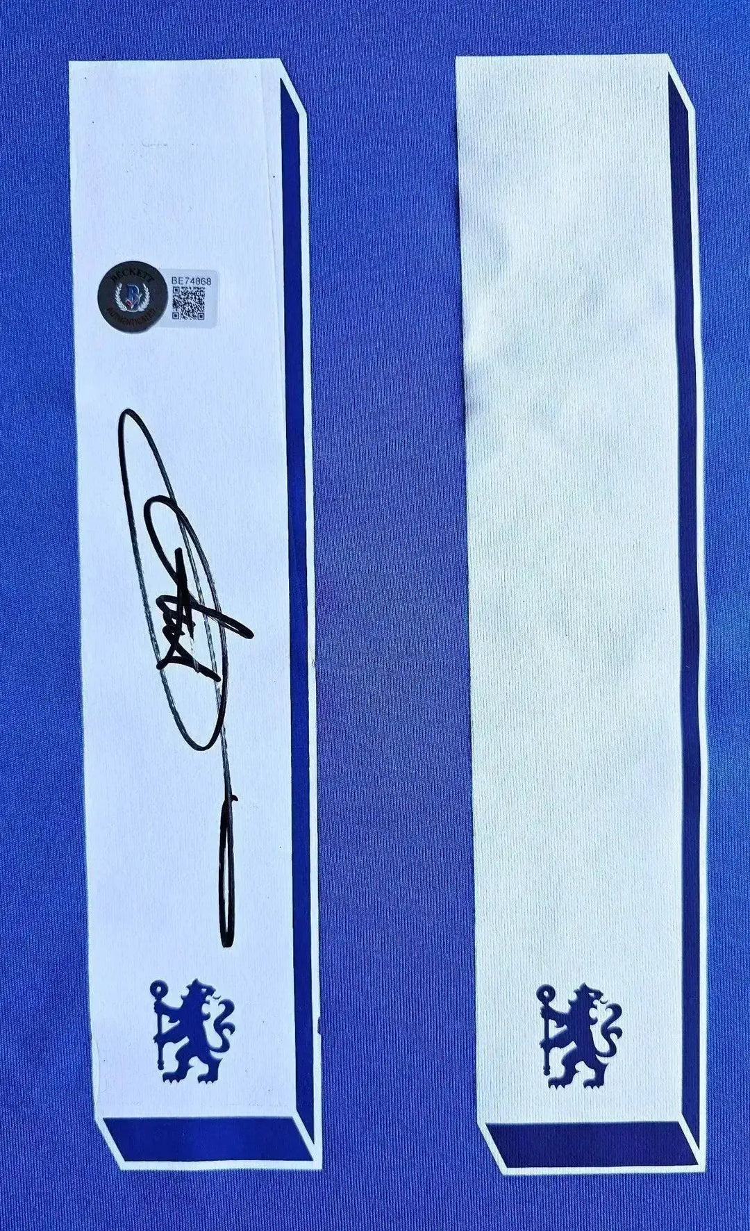 Signature detail displaying Didier Drogba's autograph on white details with Chelsea crest.