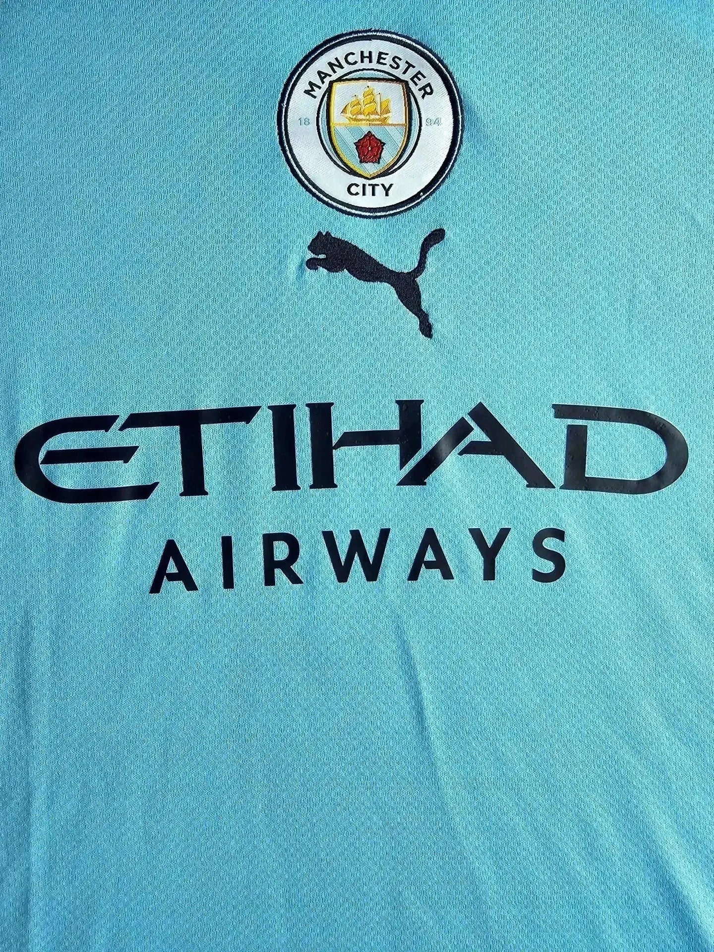 Crest of Manchester City F.C. featuring black Puma logo and Etihad Airways sponsorship.