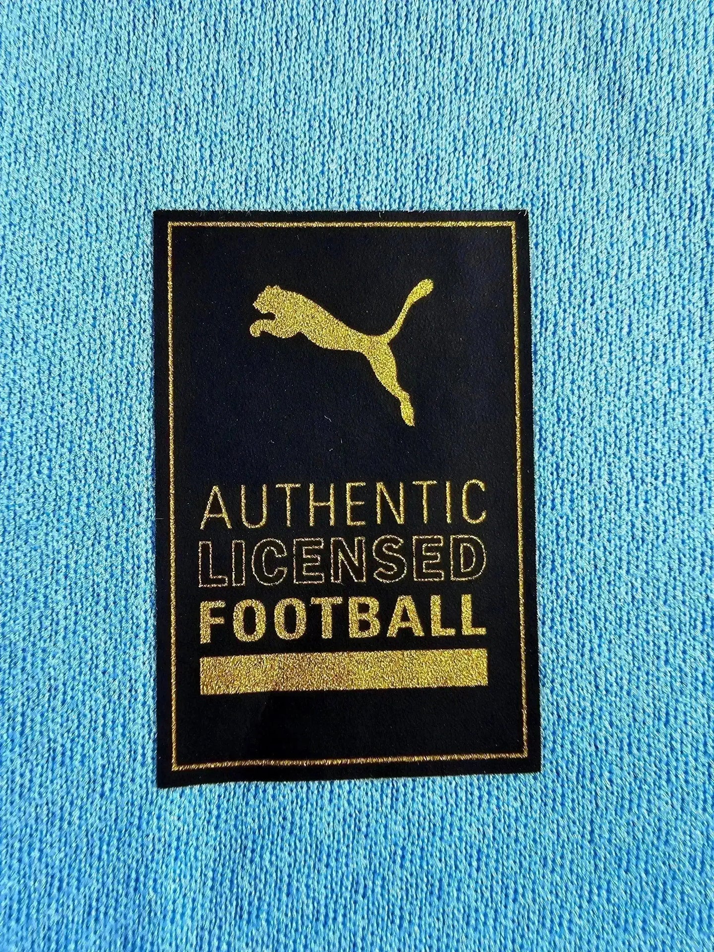 Detail showing the 'AUTHENTIC LICENSED FOOTBALL' tag with a gold Puma logo.