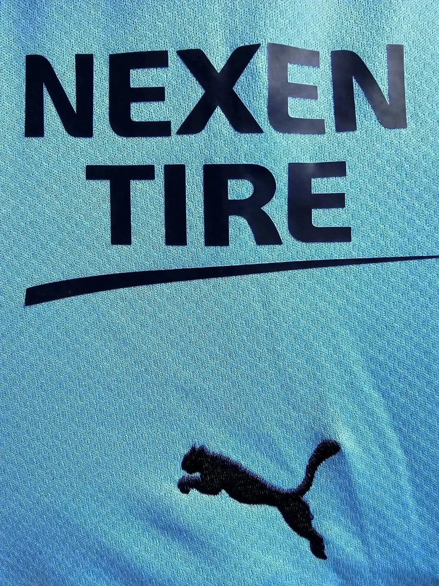 Detail view showing NEXEN TIRE sponsor logo and Puma emblem on a light blue soccer jersey.