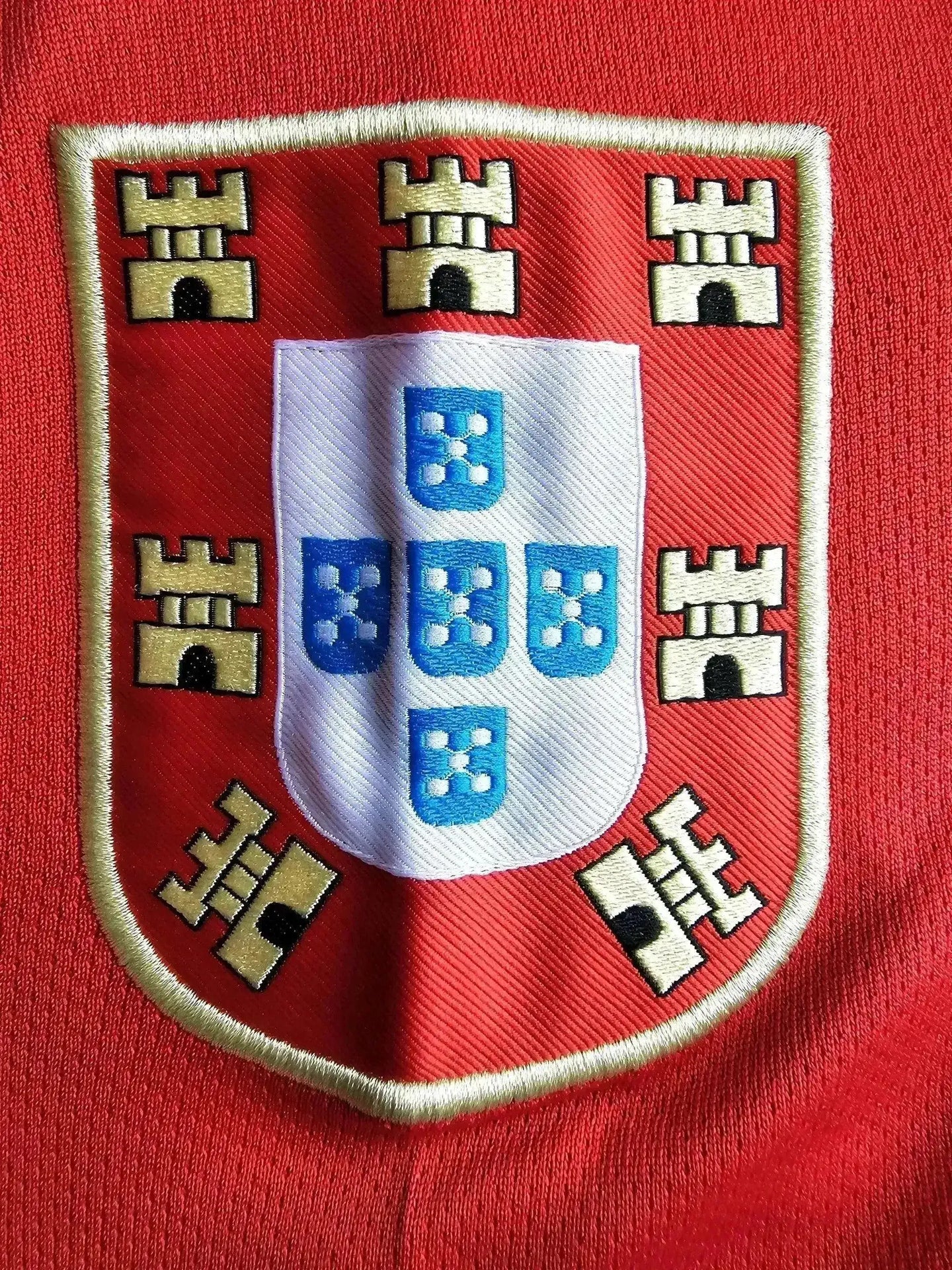 Crest detail featuring the Portugal national emblem with blue shields and castles on a red background.