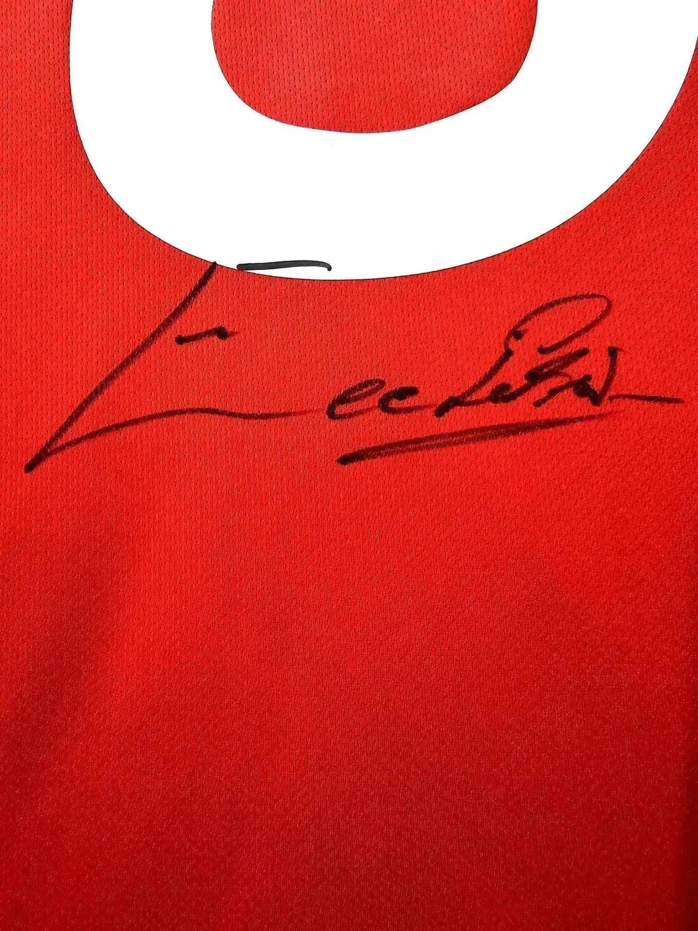 Close-up view of the signature on the Eusebio 8 S.L. Benfica soccer jersey in red.