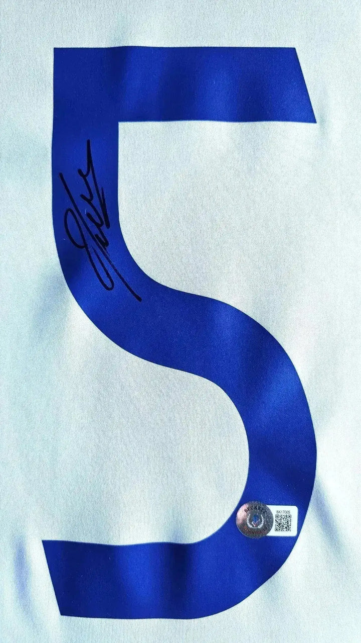 Detail view featuring signature and No. 5 on the white fabric of the signed football shirt.